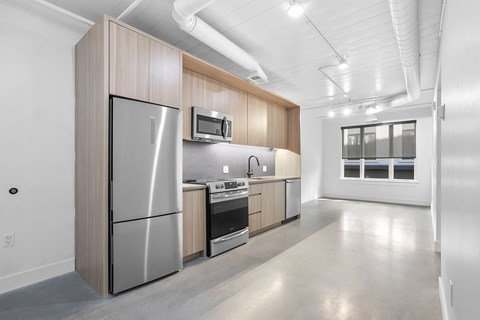 an empty kitchen with stainless steel appliances and wooden cabinets