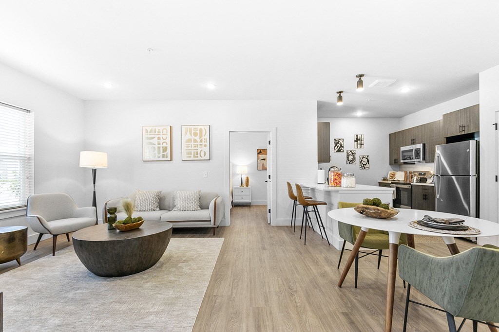 A modern living room with a dining area and kitchen in the background.