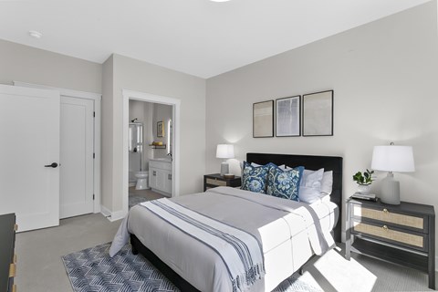 A bedroom with a large bed and a nightstand with a lamp.