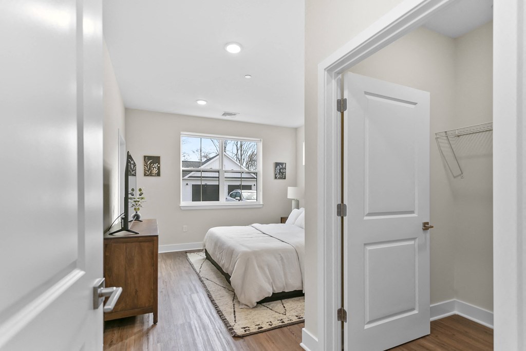 A bedroom with a bed, nightstand, and a window.