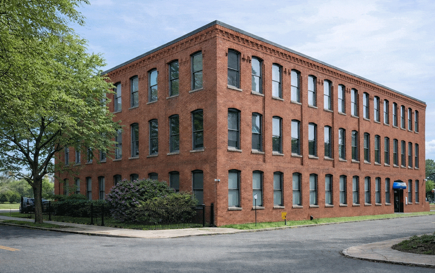 A red brick building with green bushes in front.