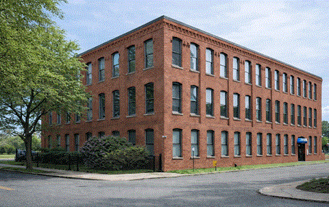 A red brick building with green bushes in front.