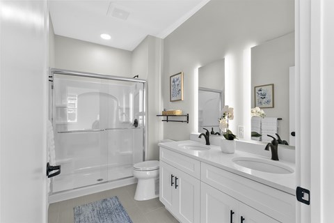 A white bathroom with a glass shower door and a white toilet.