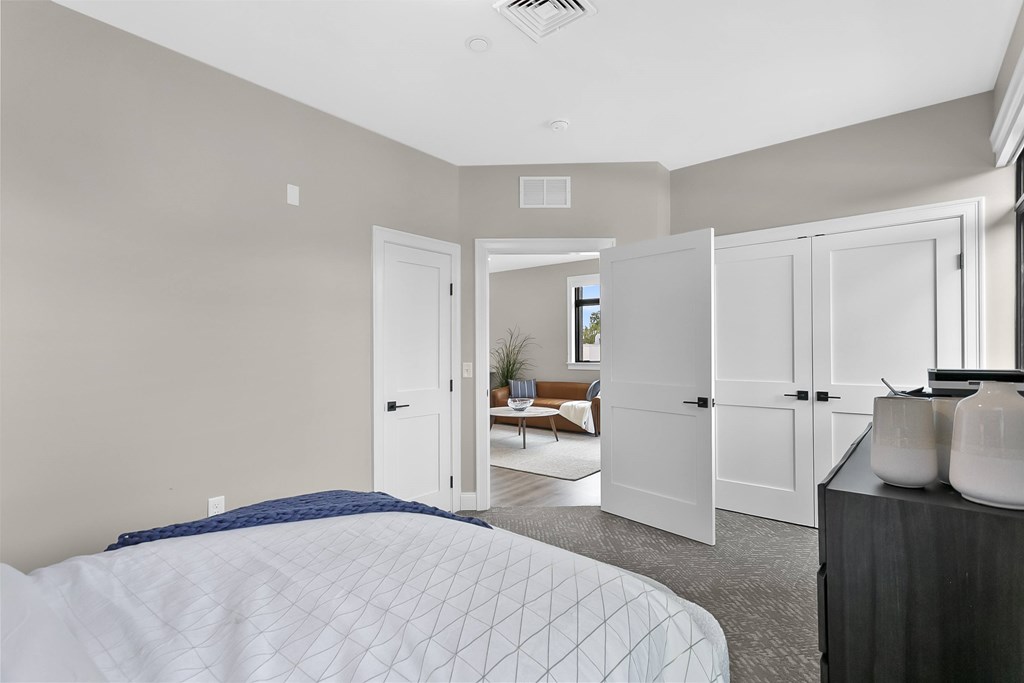 A bedroom with a large bed and a couch in the background.