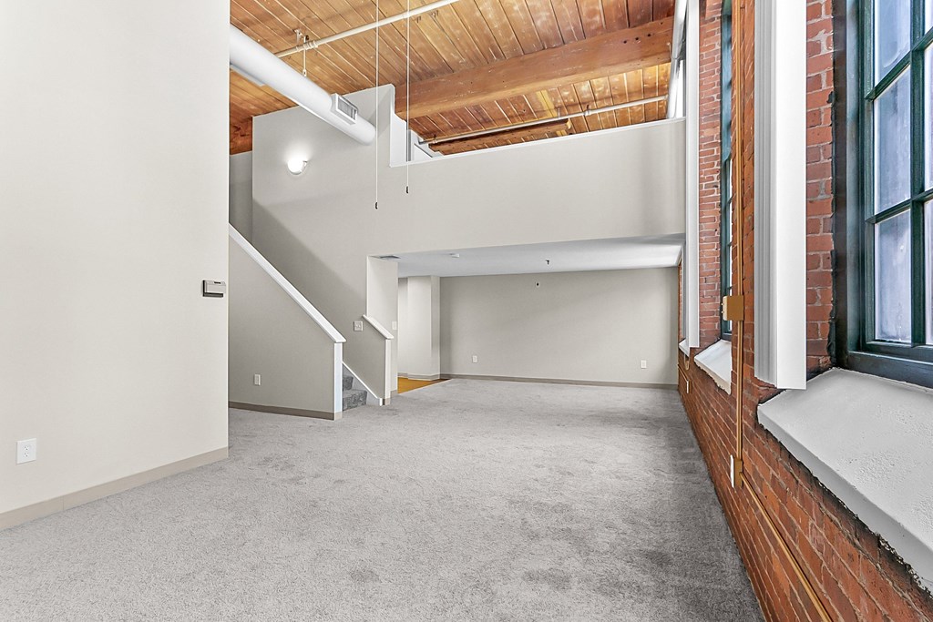 an empty room with a brick wall and a window at Clocktower and Velvet Mill Apartments, Connecticut, 06040