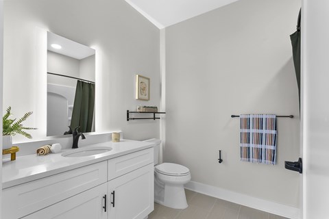 A white bathroom with a toilet, sink, and mirror.