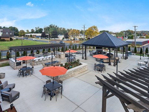 A gazebo with red umbrellas is surrounded by tables and chairs.
