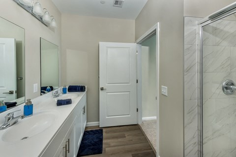 a bathroom with a shower and a sink and a mirror at Eden & Main 55+ Apartments, Southington