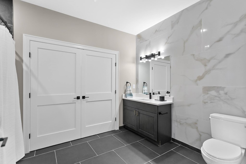 A bathroom with a marble wall and a white toilet.