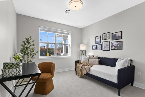 A bedroom with a bed, chair, and table.
