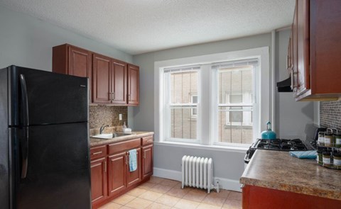 A kitchen with brown cabinets and a black refrigerator.