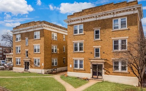 A two-story brick building with a green lawn in front.
