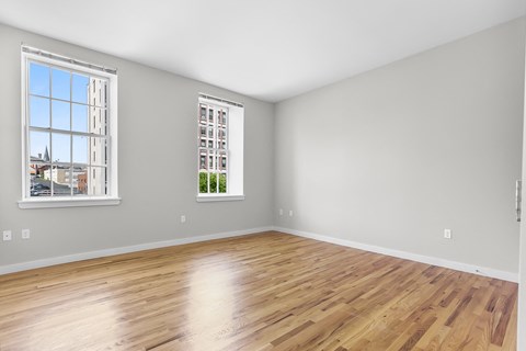 an empty room with wood floors and two windows at 1188 Lofts, Bridgeport