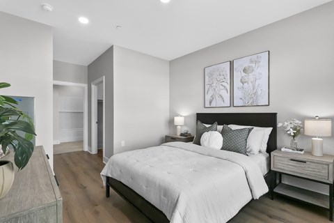 A bedroom with a large bed and a nightstand with a lamp.