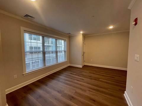 an empty living room with a large window and wooden floors