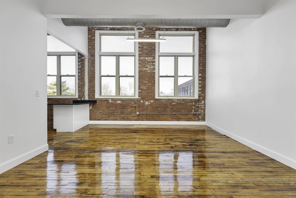 A room with a wooden floor and a brick wall.