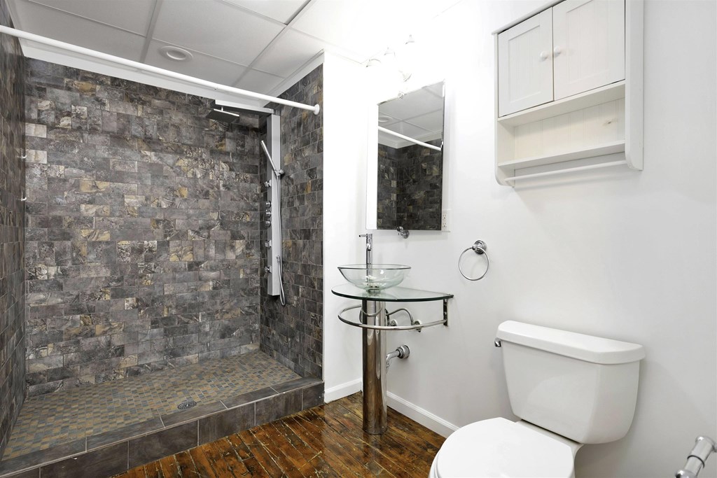A bathroom with a stone shower and a toilet.