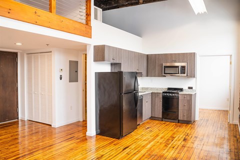 A kitchen with a black fridge and wooden floors.