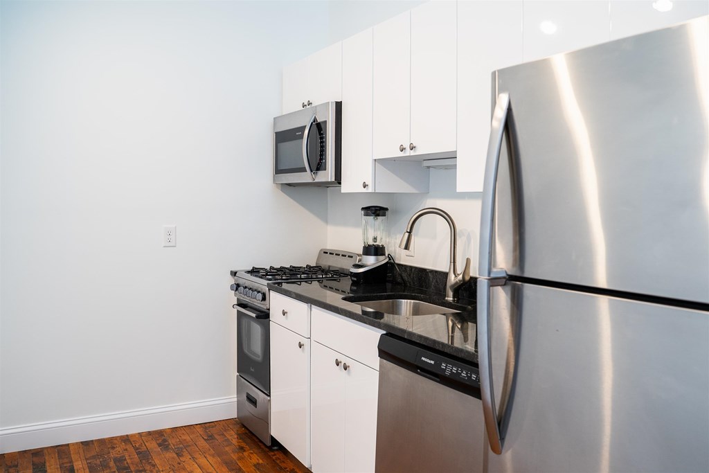 A modern kitchen with a stainless steel refrigerator, microwave, and oven.