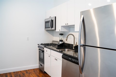 A modern kitchen with a stainless steel refrigerator, microwave, and oven.