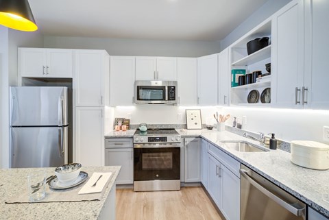 A kitchen with a granite countertop and stainless steel appliances.