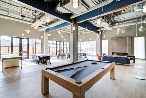 A pool table is in the middle of a room with a lot of windows.
