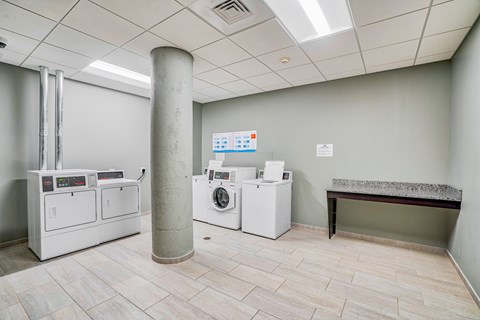 a laundry room with washer and dryers and a table at Cherry Street Lofts in Bridgeport, CT, 06605