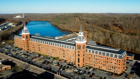 an aerial view of a large building next to a river at Ponemah Mills in Taftville, CT, 06380