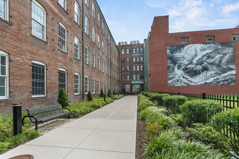 a sidewalk in front of a building with a large mural on the side at 1188 Lofts, Bridgeport, CT