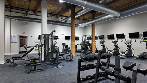 A gym with a variety of equipment including treadmills, weights, and exercise machines.