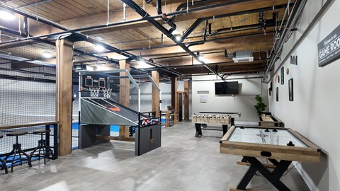 A basketball court is located in the middle of a room with a pool table and air hockey table.