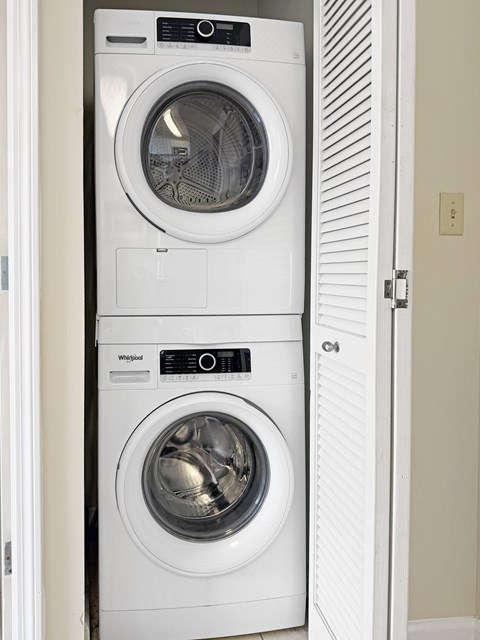 A white Whirlpool washing machine and dryer in a small laundry room.