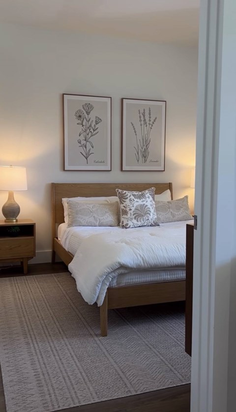 A bedroom with a bed, nightstand, and two framed pictures on the wall.
