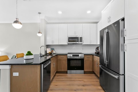 A modern kitchen with a black countertop and stainless steel appliances.