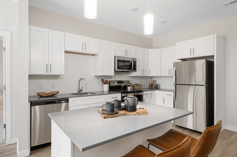 A modern kitchen with white cabinets and stainless steel appliances.