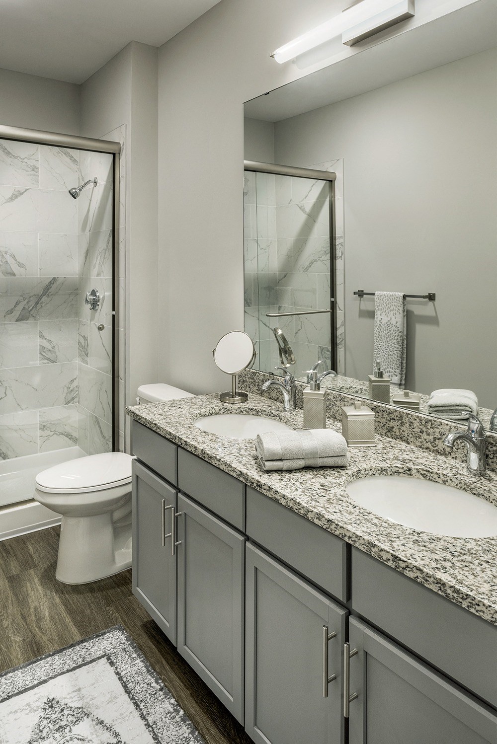 a bathroom with two sinks and a shower and a toilet at The Beacon at Gateway Apartments, Scarborough, ME, 04074