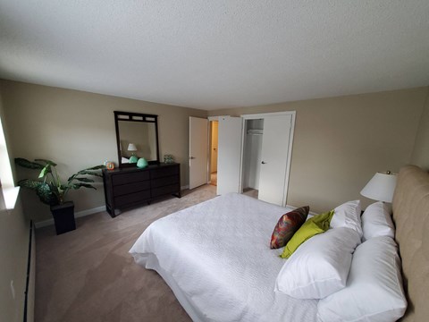 a bedroom with a large white bed and a dresser with a mirror at Greenfield Village Apartments, Rocky Hill