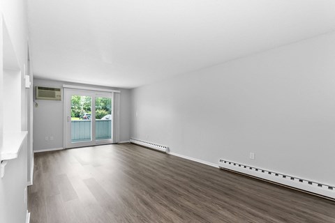 an empty living room with wood floors and a door to a balcony