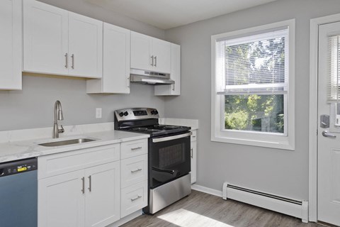 a kitchen with white cabinets and a stove and a window at Hawkins Meadow in Amherst, MA, 01002