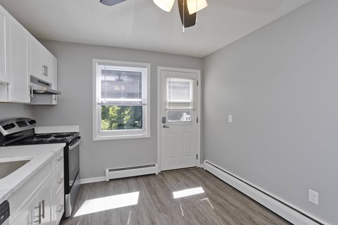 an empty kitchen with white cabinets and a white door and window at Hawkins Meadow in Amherst, MA, 01002