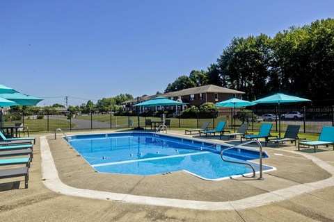 a swimming pool with blue chairs and umbrellas