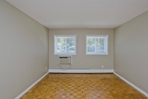 an empty living room with two windows and a wood floor at Park Edge, Springfield, MA