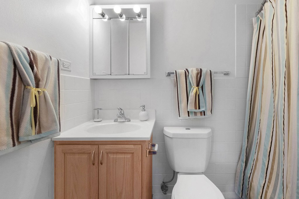a small bathroom with a toilet and a sink at St Charles Square Apartments, Carol Stream, IL
