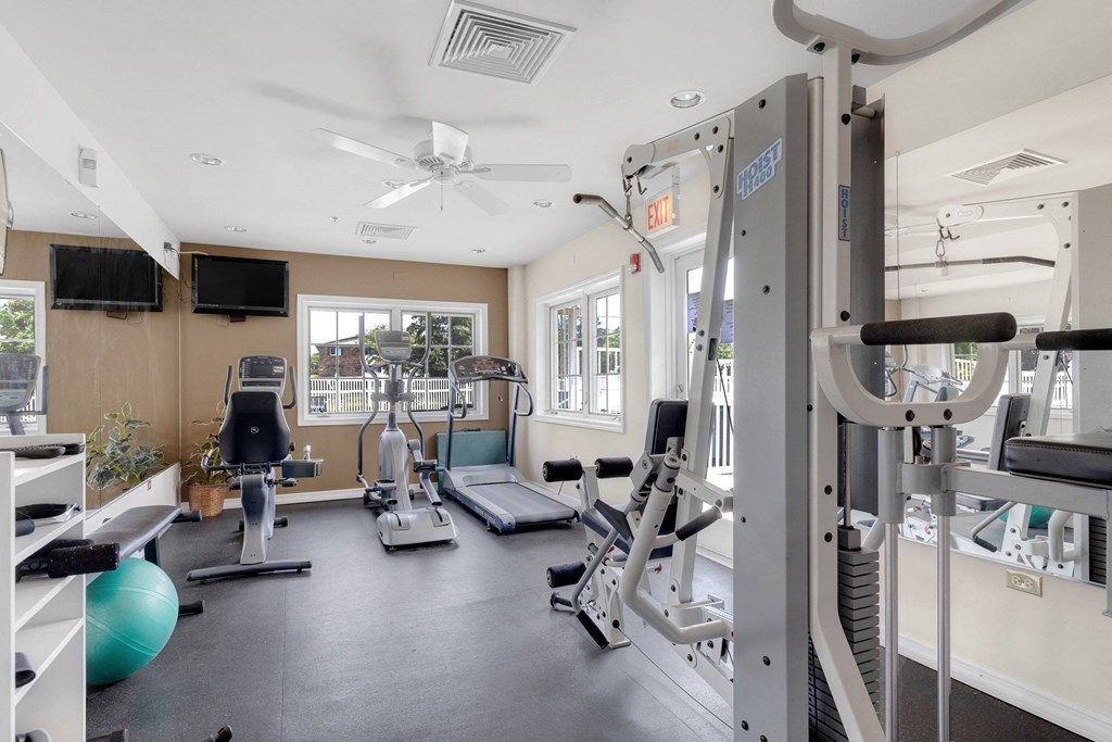 a gym with weights and cardio equipment and a window at St Charles Square Apartments, Carol Stream
