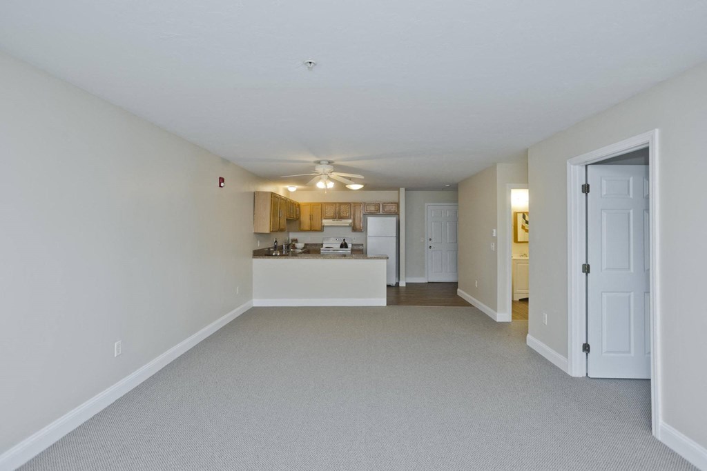the living room and kitchen of an empty house with a ceiling fan
