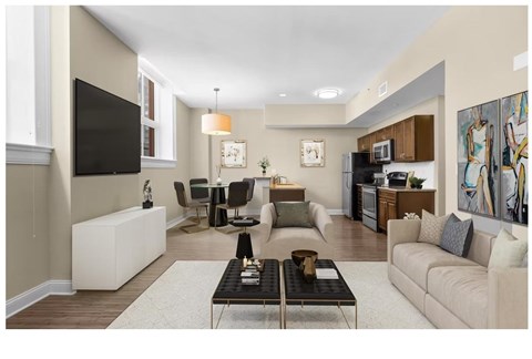 A living room with a white sofa, a black coffee table, and a television on the wall.