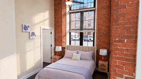 A bedroom with a large bed and a window with blinds.