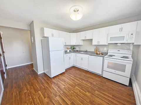 A kitchen with white appliances and wooden floors at Rose Hill Estates, Norwich, CT, 06360