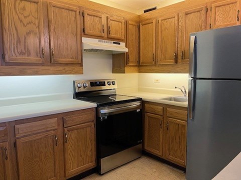 A kitchen with wooden cabinets and a stainless steel refrigerator.