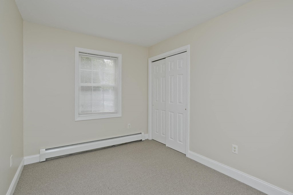 a bedroom with white walls and a white door and a window